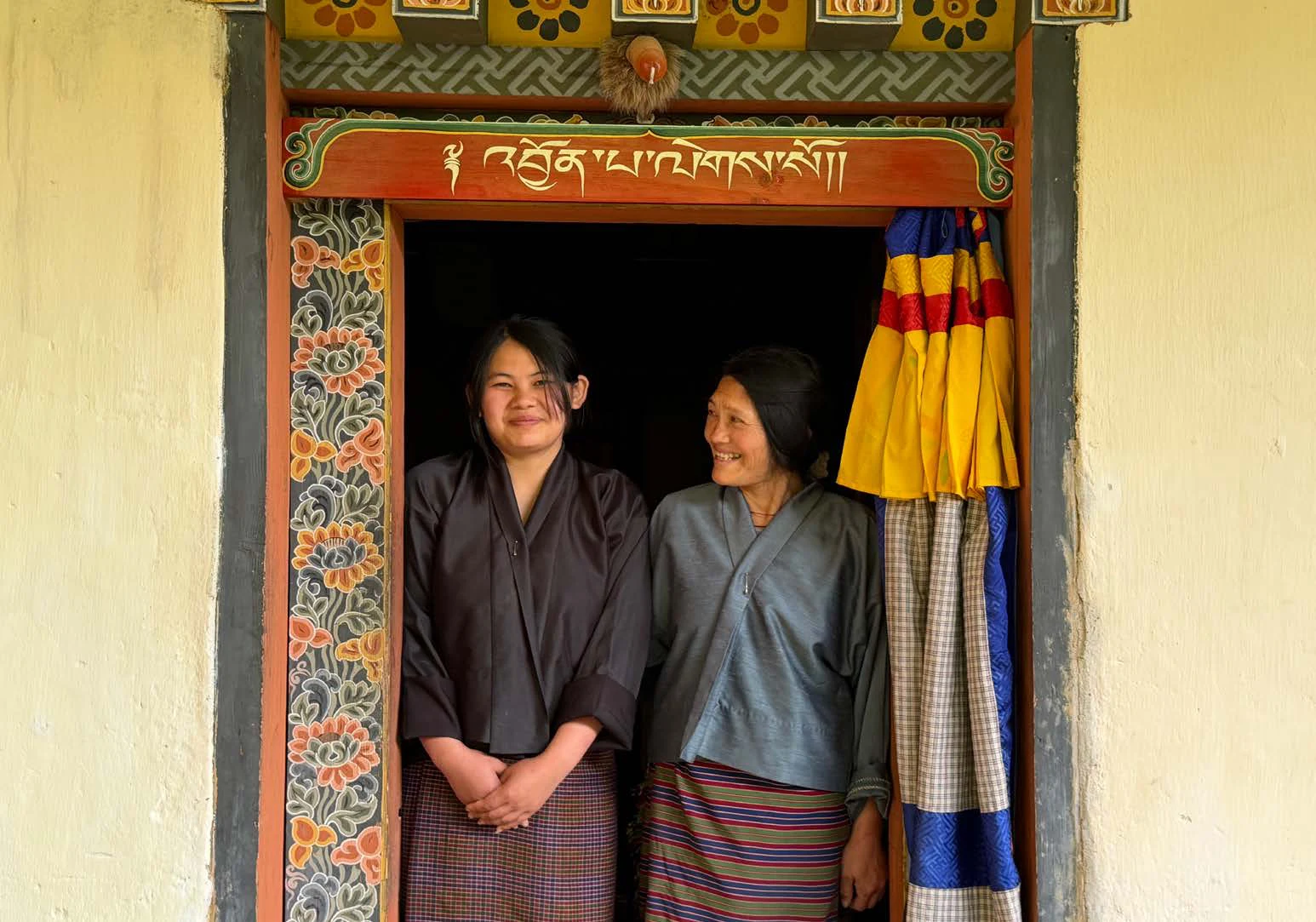Two women in a richly painted Bhutanese doorway
